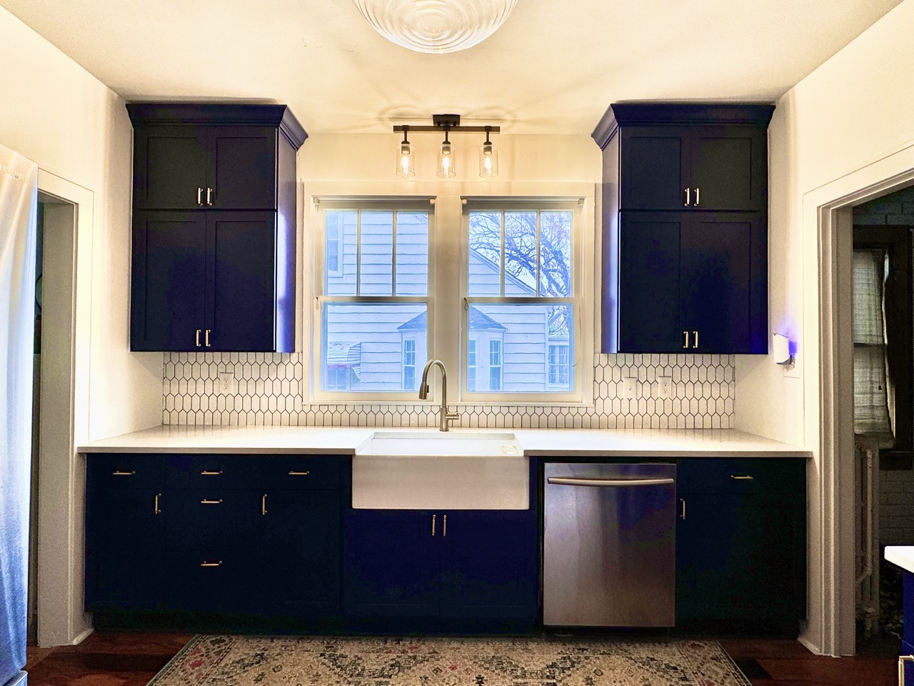 Kitchen after remodel — navy cabinets, farmhouse sink, hex backsplash