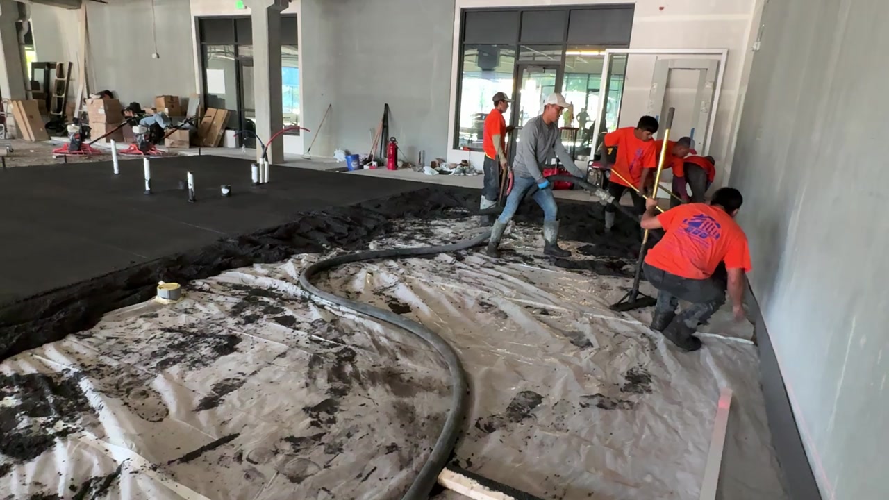 Full crew pouring concrete in commercial building