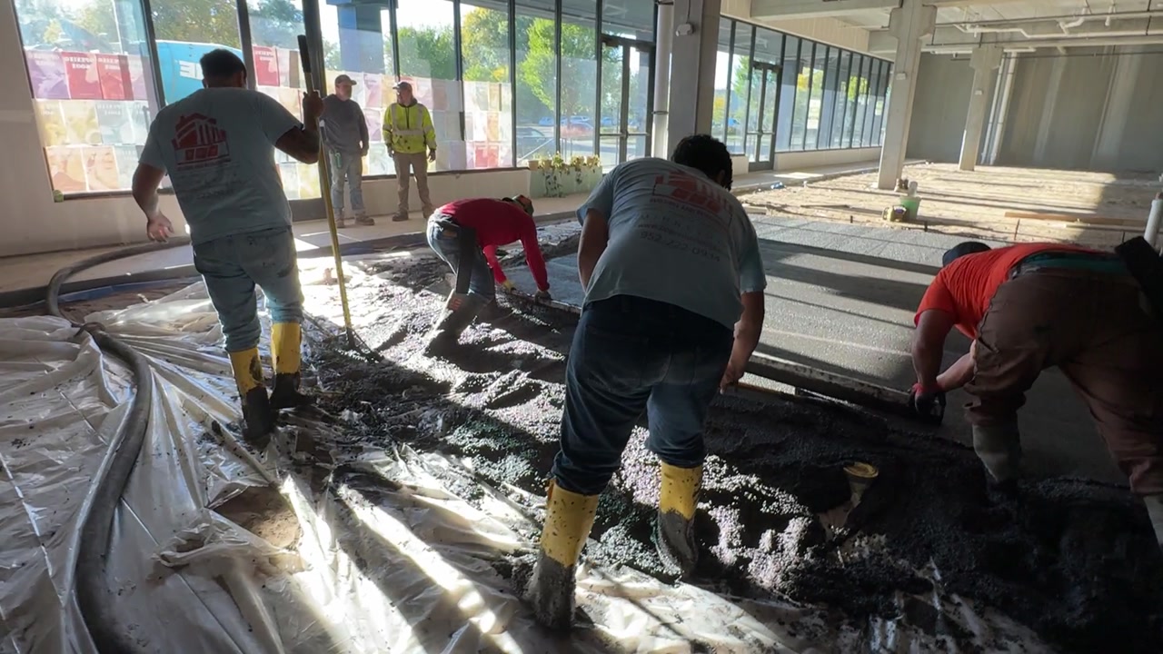 Full tenant buildout — crew spreading concrete in commercial space