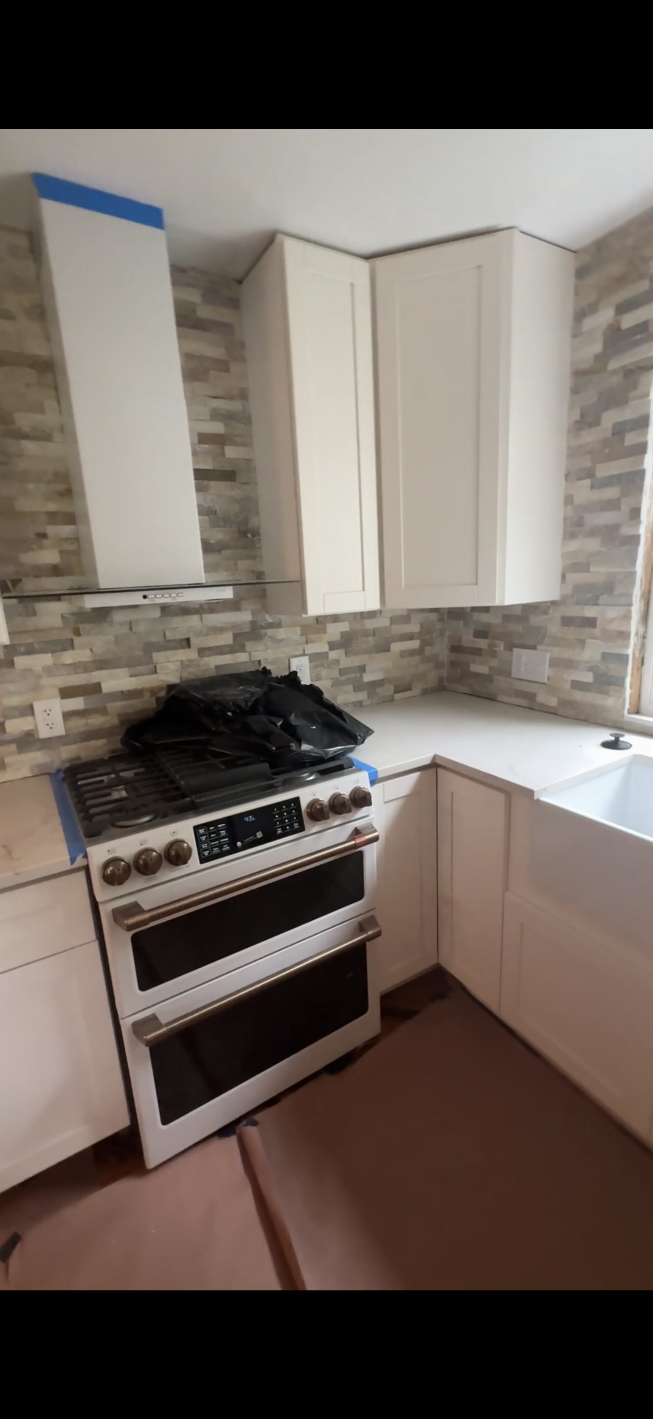Kitchen remodel complete — stove, range hood, and stone backsplash