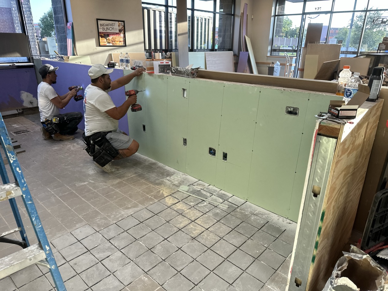 Crew installing drywall behind commercial counter